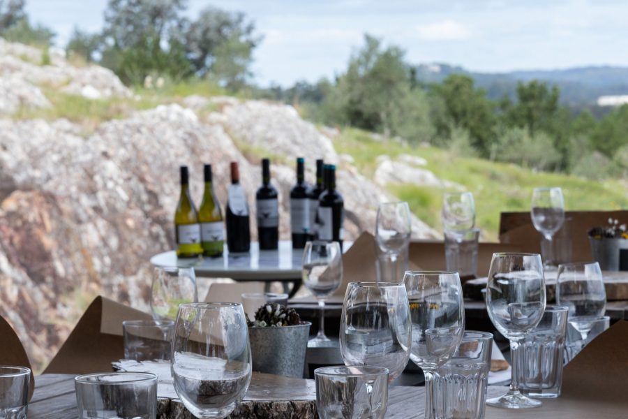 Copas de vino sobre una mesa con vista panorámica a la Laguna del Sauce en Bodega Alto de la Ballena.