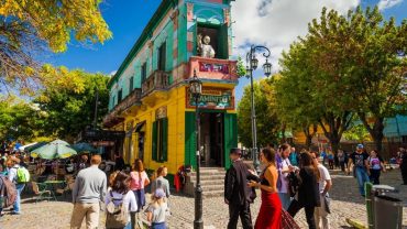 Calle colorida de Caminito en el barrio de La Boca, Buenos Aires, con casas de chapa y arte callejero.